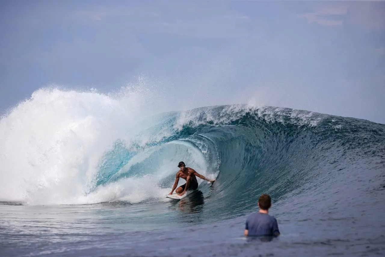 Surfer beside a breaking reef wave